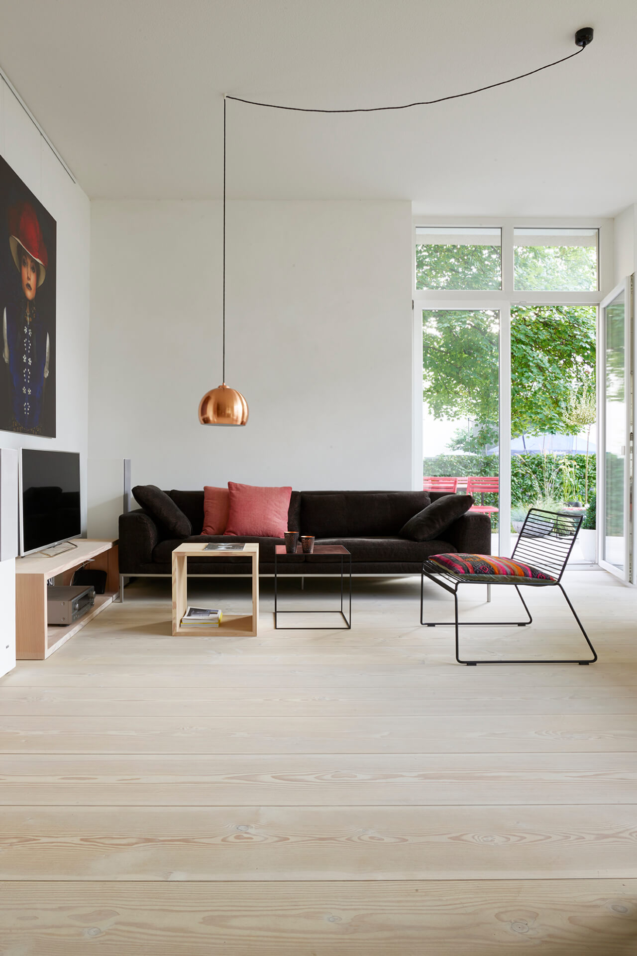 Large open plan living room with light Douglas fir floorboard and dark sofa