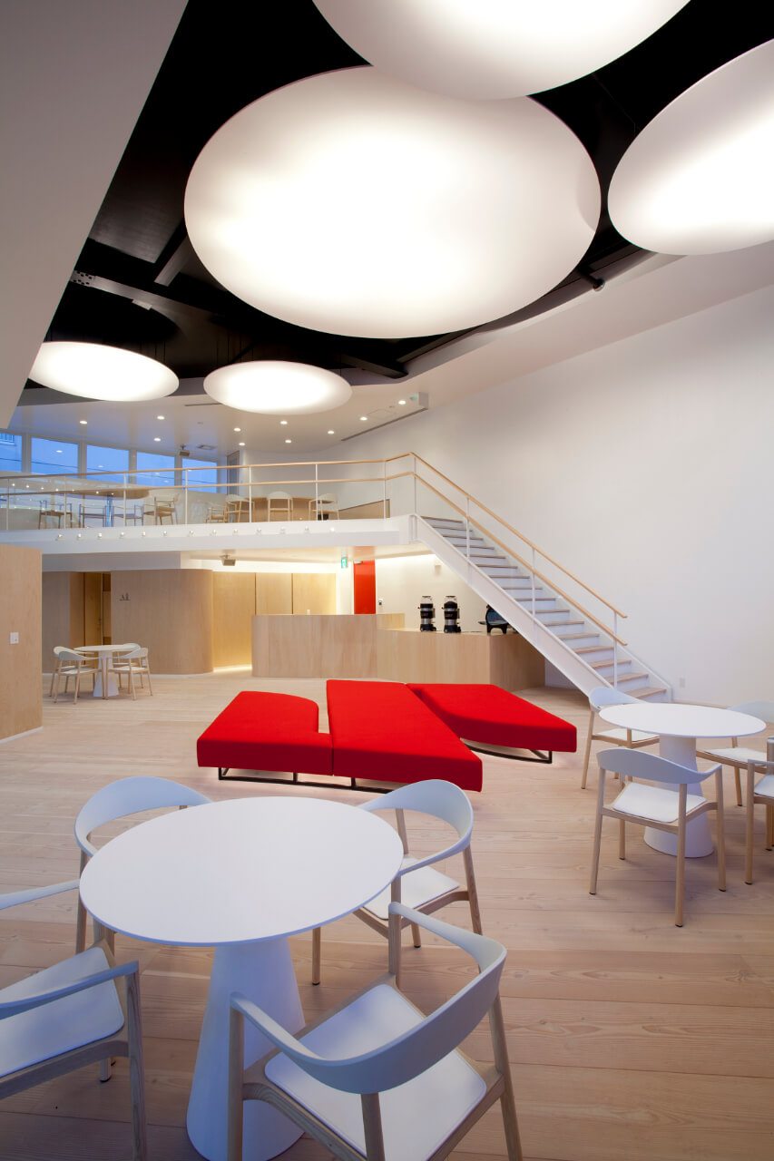 Large bright showroom with light plank flooring and red S-shaped sofa